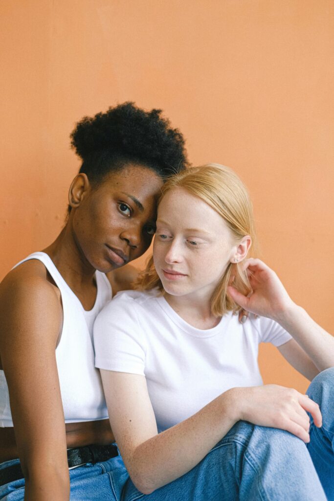 A loving and intimate moment between an interracial couple in white shirts against an orange backdrop.